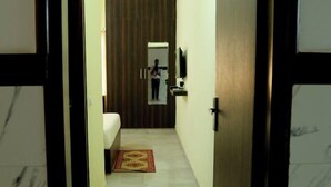Pasillo de hotel con una cama, un espejo y una puerta.