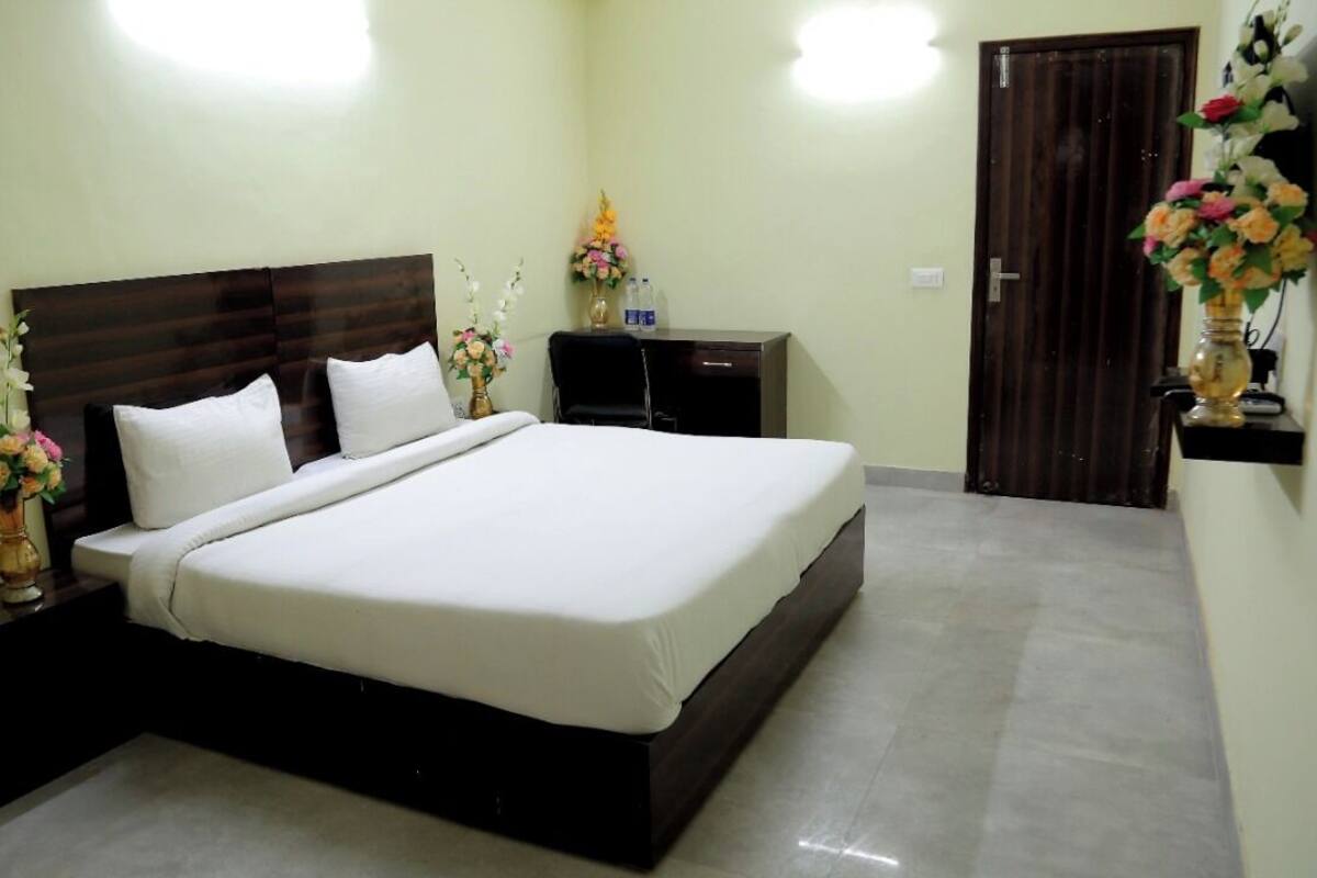 A neatly arranged bedroom with a large bed, bedside tables, a desk, and a wardrobe.