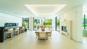 A modern kitchen with a dining area, large windows, and a flat-screen TV. - Magnificient 5 bed villa in Golden Mile Marbella (Marbella)