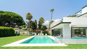 A modern house with a swimming pool, a well-maintained lawn, and a patio with lounge chairs. - Magnificient 5 bed villa in Golden Mile Marbella (Marbella)