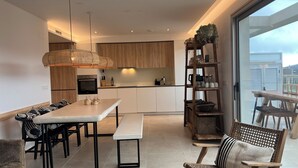 Une cuisine moderne avec des meubles en bois, un coin repas doté d’un banc et une vue sur la ville grâce à de grandes fenêtres.