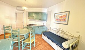 A compact kitchen with green cabinets, a dining table with chairs, and a sofa with patterned cushions. - Relaxing Le Residenze del Maria Rosaria No2300 (Orosei)