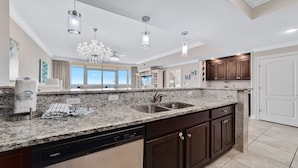 A modern kitchen with granite countertops, stainless steel appliances, and dark wooden cabinets. - Phoenix Orange Beach!  Lazy River and Slide !  New Rental!! (Orange Beach)