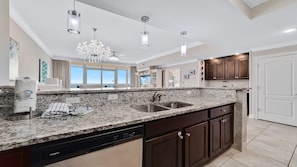 A modern kitchen with granite countertops, stainless steel appliances, and dark wooden cabinets.