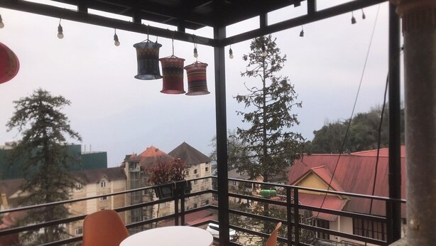 Un balcón con una mesa y sillas, con vista a una zona residencial con casas y árboles.