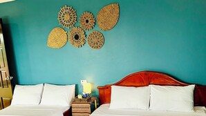 Habitación de hotel con dos camas, una pared color aguamarina y decoración mural.