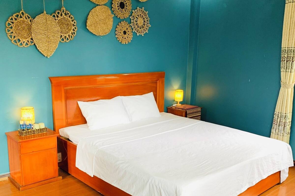 Ein Schlafzimmer mit einem hölzernen Bett, weißer Bettwäsche und einer türkisblauen Wand.