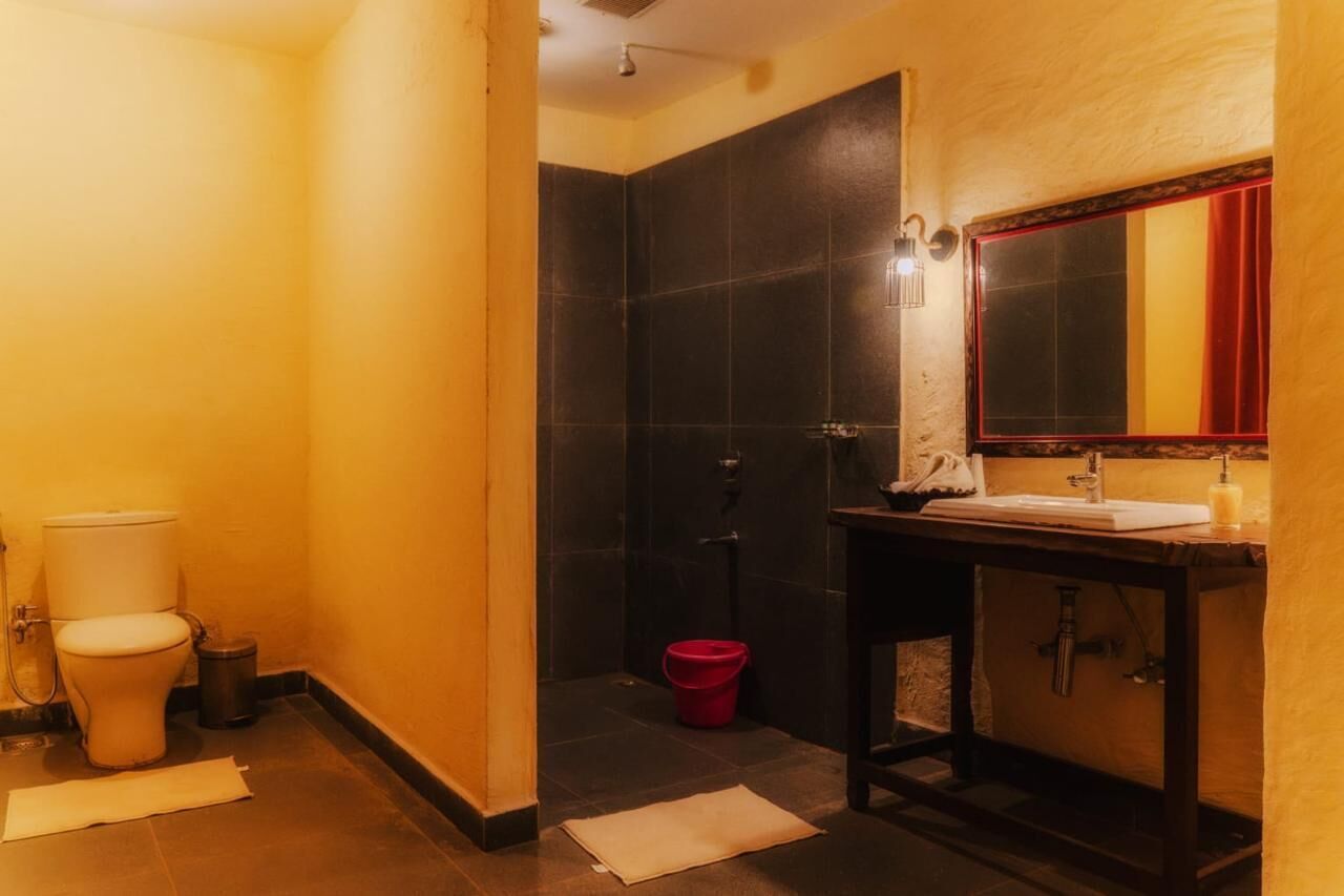 A bathroom with a toilet, sink, mirror, and shower area.