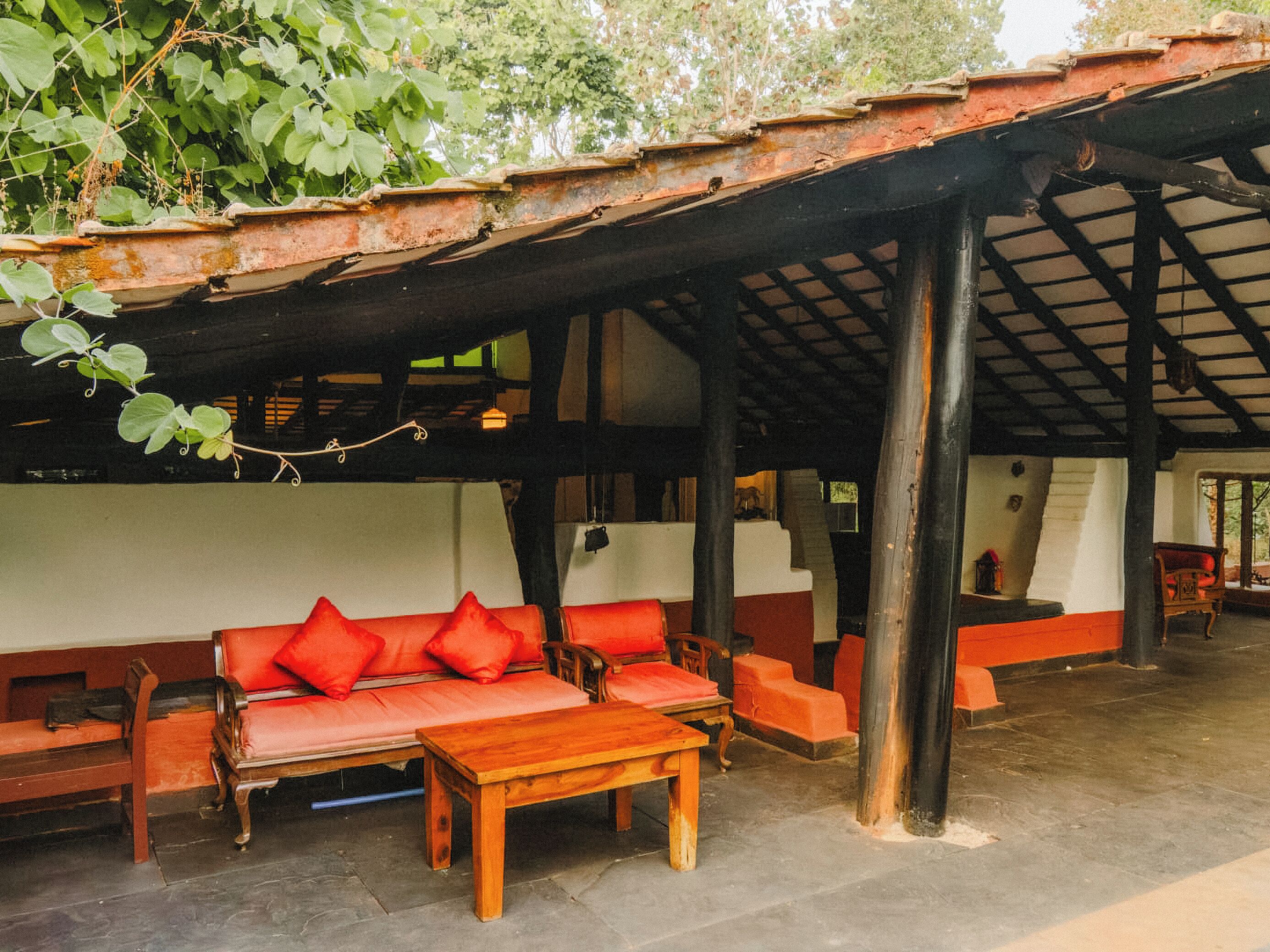 A covered outdoor seating area with wooden furniture and a tiled floor.