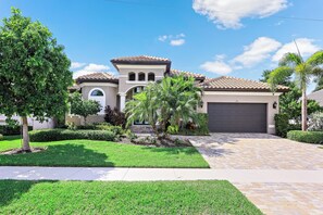A residential house with a tiled roof, a garage, and a well-maintained lawn. - Waterfront Home | W Exposure, Pool & Spa (Marco Island)