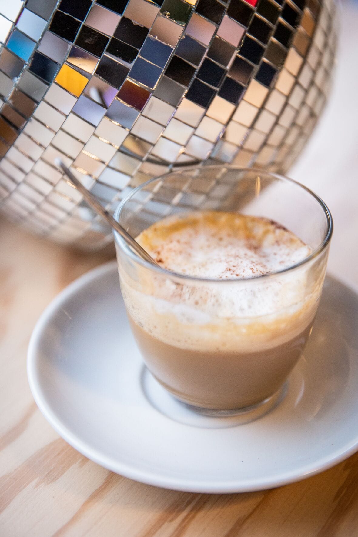 Een kop koffie met een lepel, op een witte schotel.
