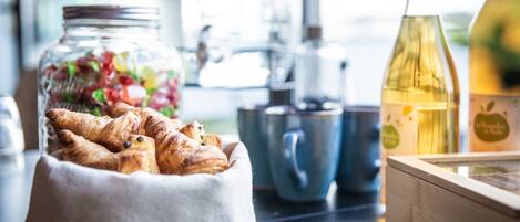 Una encimera de cocina con un tarro de pasteles, una botella de aceite de oliva y una cafetera.