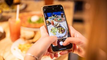 A person holding a smartphone with a photo of a meal on the screen.