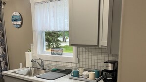 A modern kitchen with a black stovetop, a sink, and a window with a view of trees.