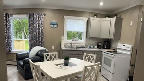 A compact kitchen with a dining area, a sofa, and a window with curtains.