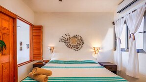 Una camera d'albergo con un letto, due comodini, un elemento decorativo a parete e una finestra con tende.