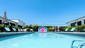 Une piscine avec des chaises longues et, en arrière-plan, un bâtiment à la façade bleue.