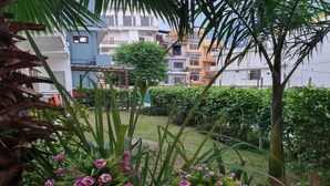 A balcony with potted plants and a view of residential buildings. - Yoga Rishi (Narendranagar)