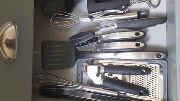 A kitchen drawer with various utensils including a whisk, spatula, and grater.