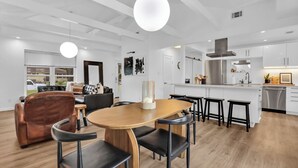 Una cocina moderna con armarios blancos, un refrigerador de acero inoxidable y una mesa de comedor de madera con sillas negras.