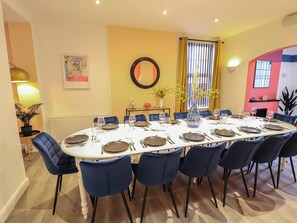 A dining area with a round table set for 12, surrounded by blue chairs. - Carlton House (Skegness)