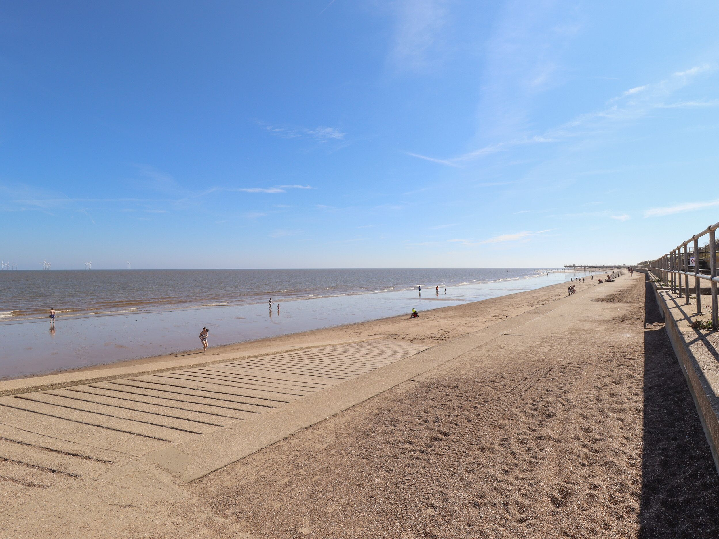 Ein Strand mit einem sandigen Weg und einer Geländer an der Seite.