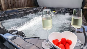 Een bubbelbad met twee glazen witte wijn en een schaal aardbeien.