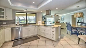 Cucina moderna con mobili bianchi, elettrodomestici in acciaio inossidabile e un'ampia finestra.
