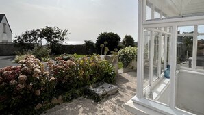 A conservatory with a view of a garden and a stone wall.