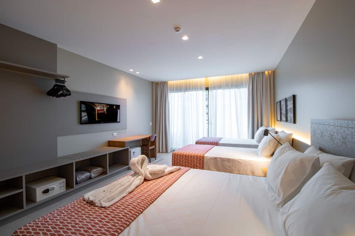 Una habitación de hotel moderna con dos camas, un escritorio, un televisor y zona de ducha.