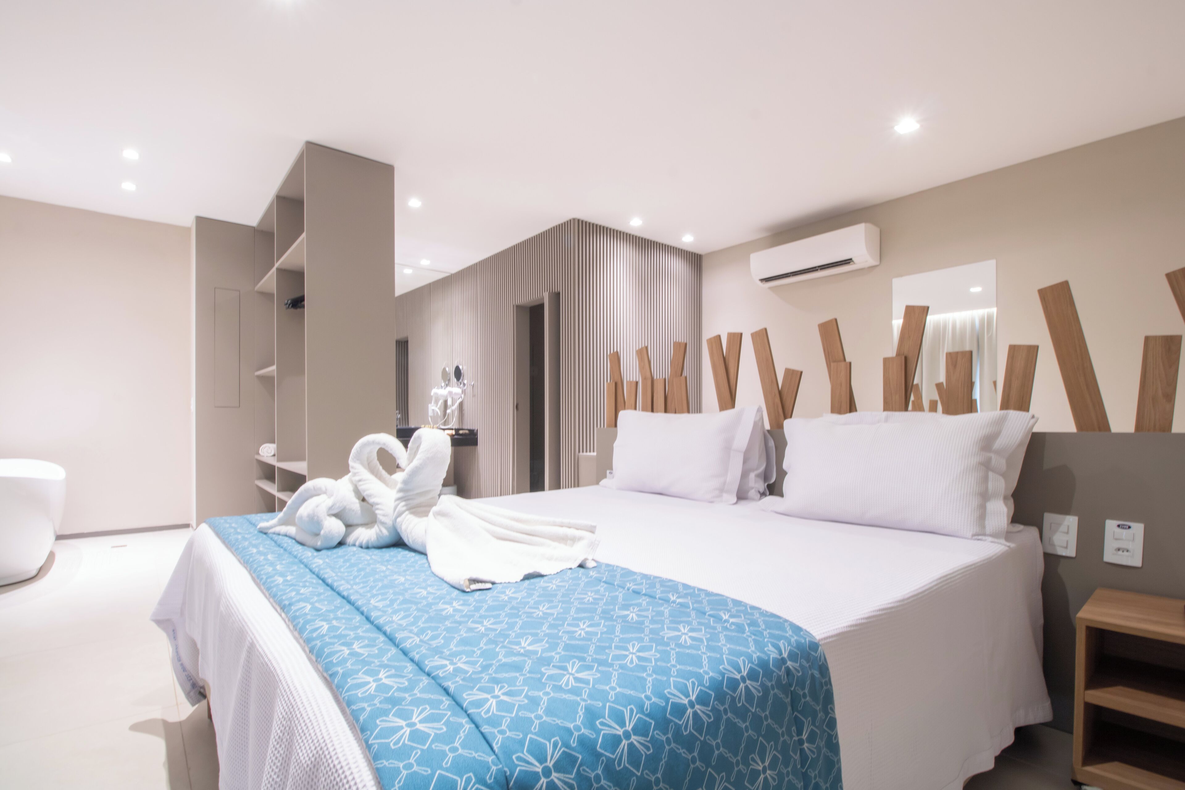A modern hotel room with a large bed, a bathroom, and a seating area.