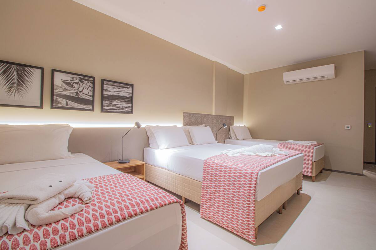 Habitación de hotel con dos camas, un ventanal grande y un ventilador de techo.