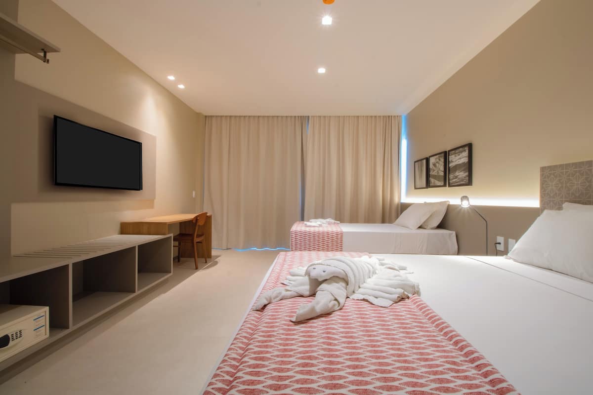 Una habitación de hotel con una cama, un escritorio, un televisor y una ventana con cortinas.