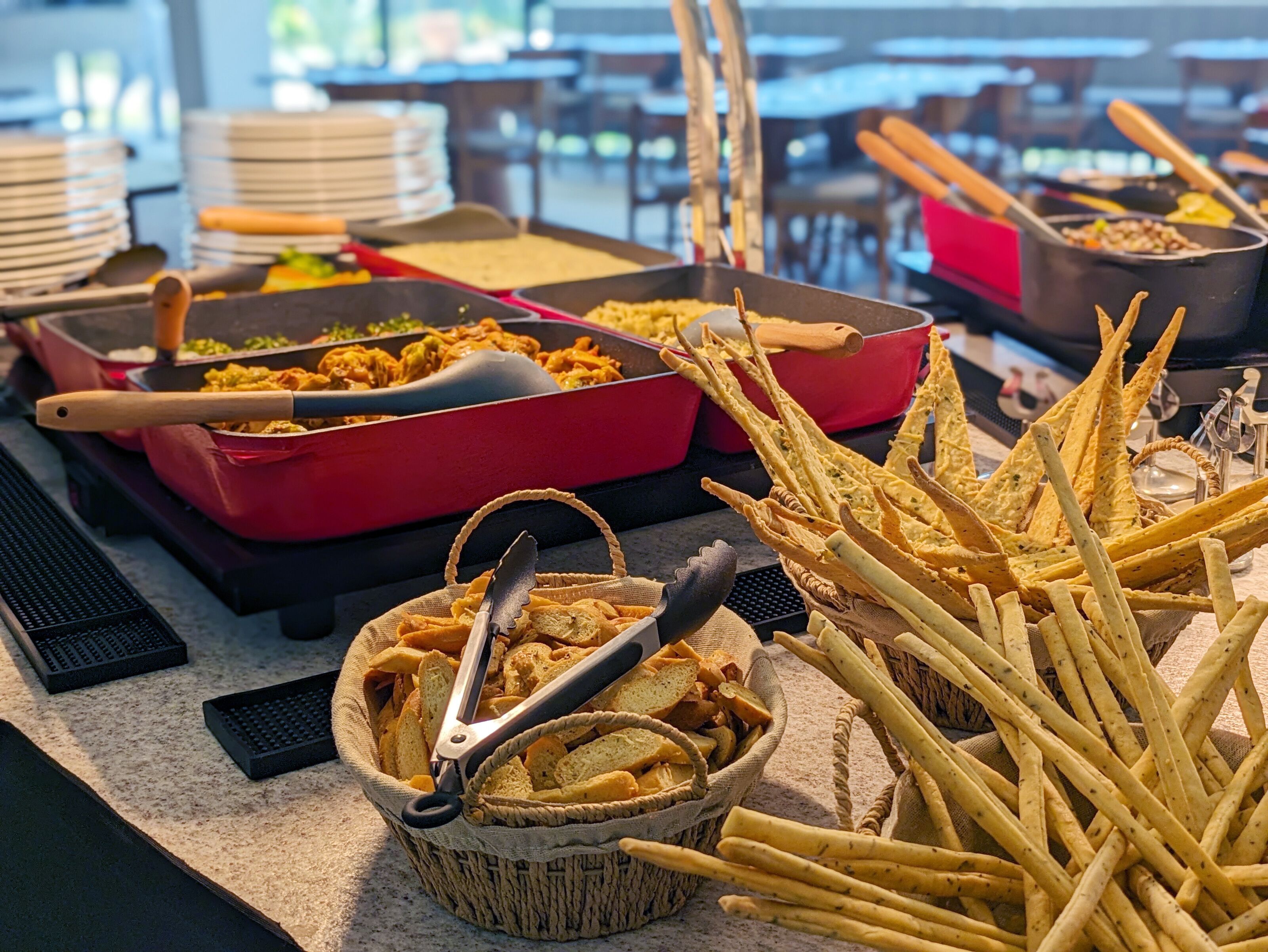 A buffet table with various food items, including bread, pasta, and fried snacks.