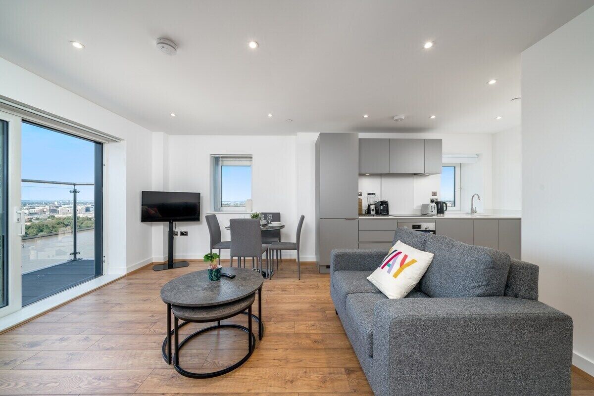 Ein modernes Apartment mit Essbereich, Küche und großem Fenster mit Blick auf eine Stadtlandschaft.