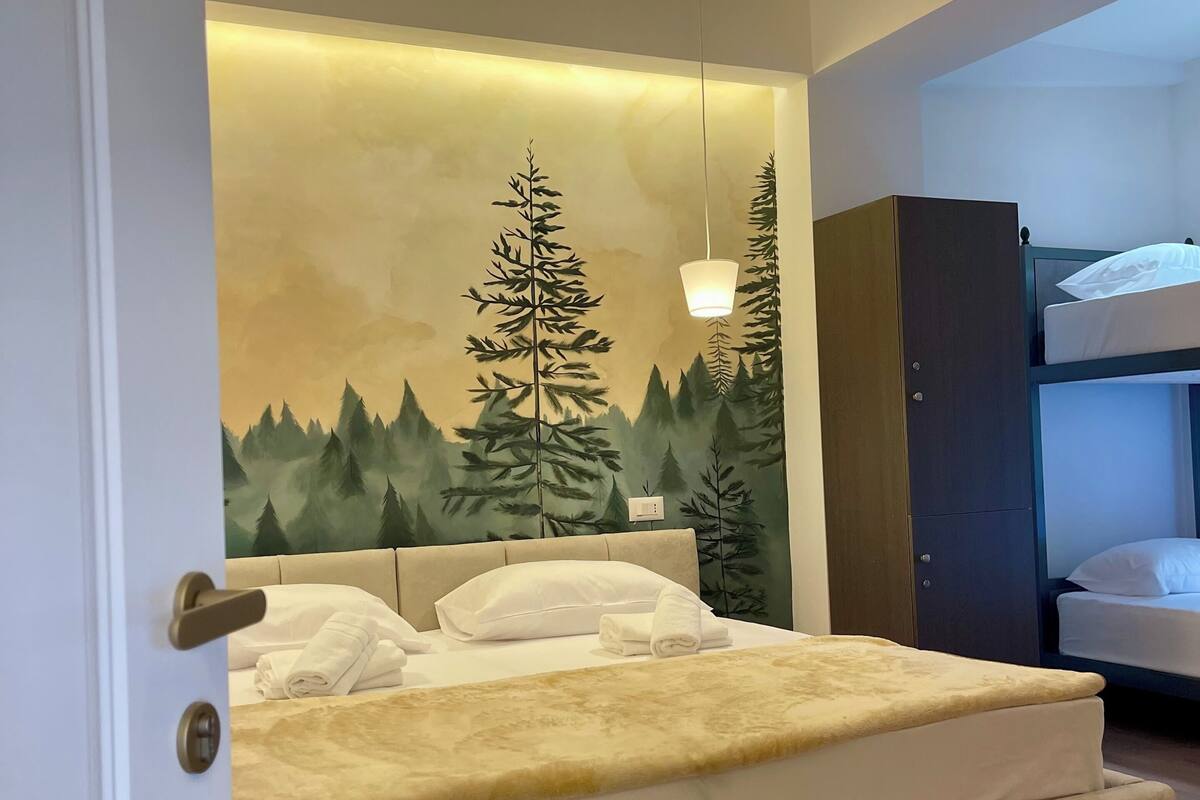 A bedroom with a bed, a hanging light fixture, a wardrobe, and a bunk bed.
