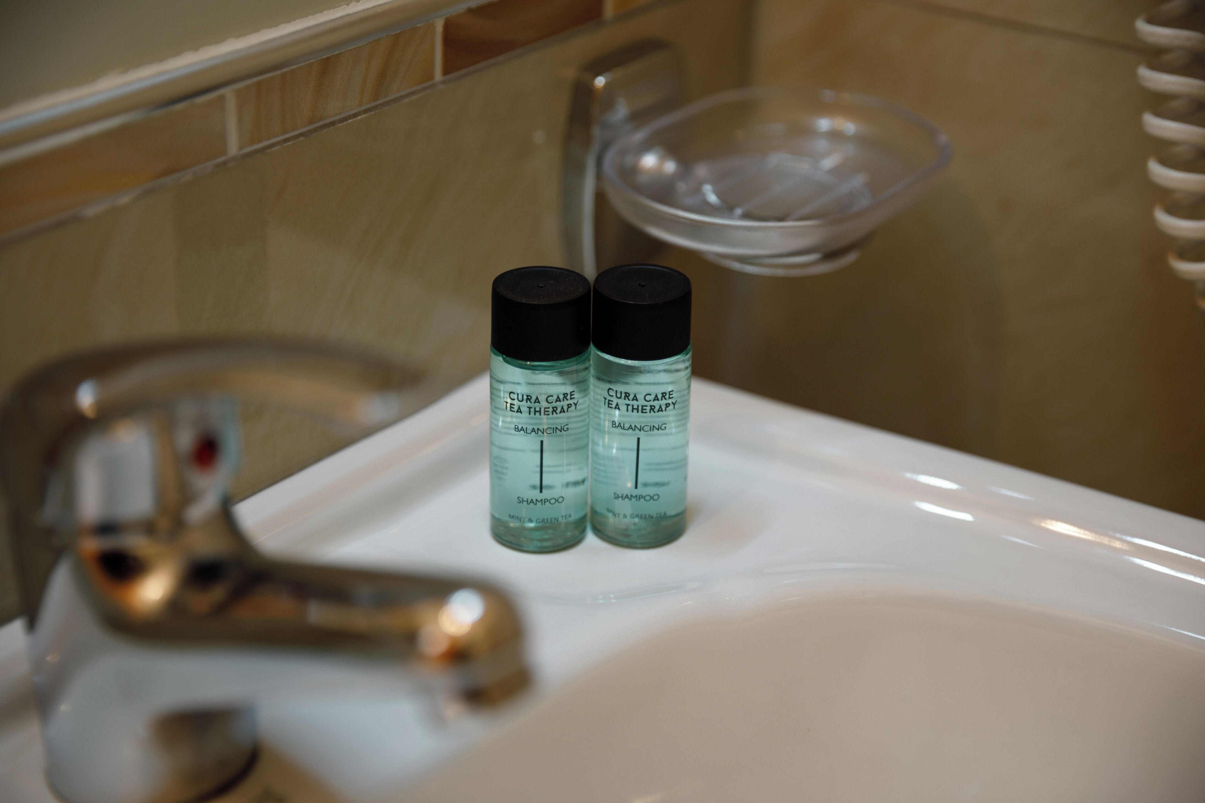 A bathroom sink with two bottles of CUA CARE Tea Therapy Balancing Shampoo.