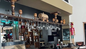 Una zona de bar con mostrador de mármol, copas colgantes, detalles de madera y una pequeña figurina.