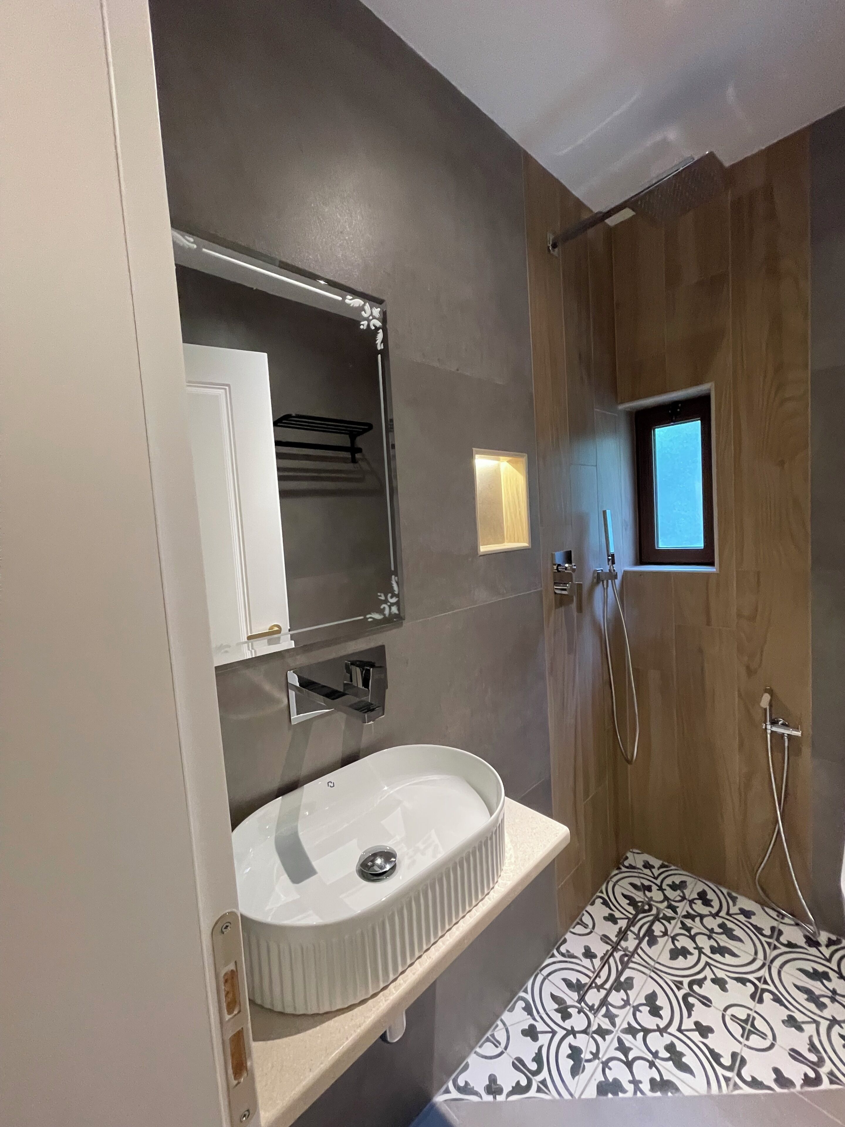 Een badkamer met een wit wastafelmeubel, een spiegel, een douche en betegelde muren.