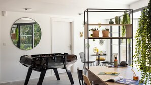 A modern room with a foosball table, a round mirror, and a plant shelf. - Apparteo Montpellier (Montpellier)