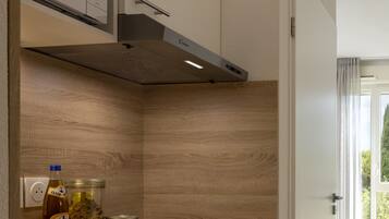 A kitchen with a microwave, stove, and a window with curtains.