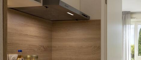 Una cocina con microondas, estufa y ventana con cortinas.