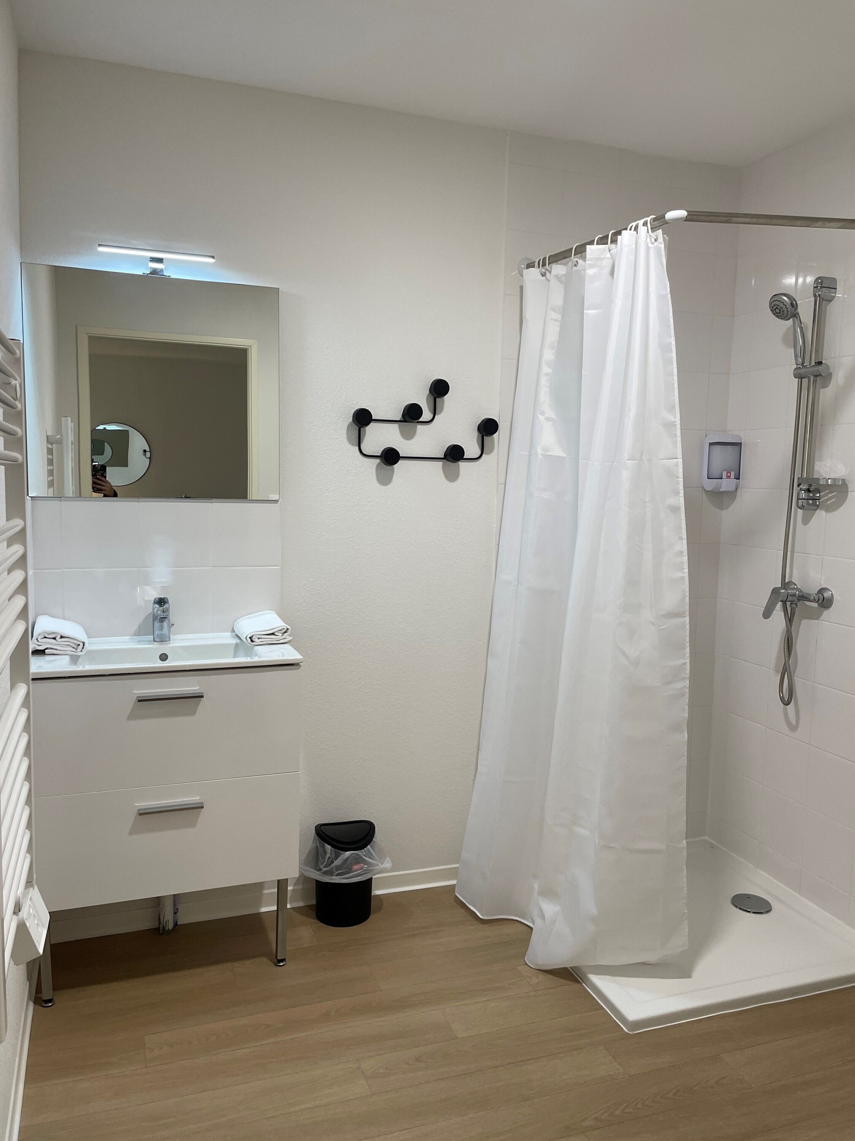 A bathroom with a shower, a sink with a mirror, and a towel rack.