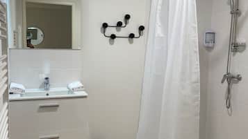 A bathroom with a shower, a sink with a mirror, and a towel rack.