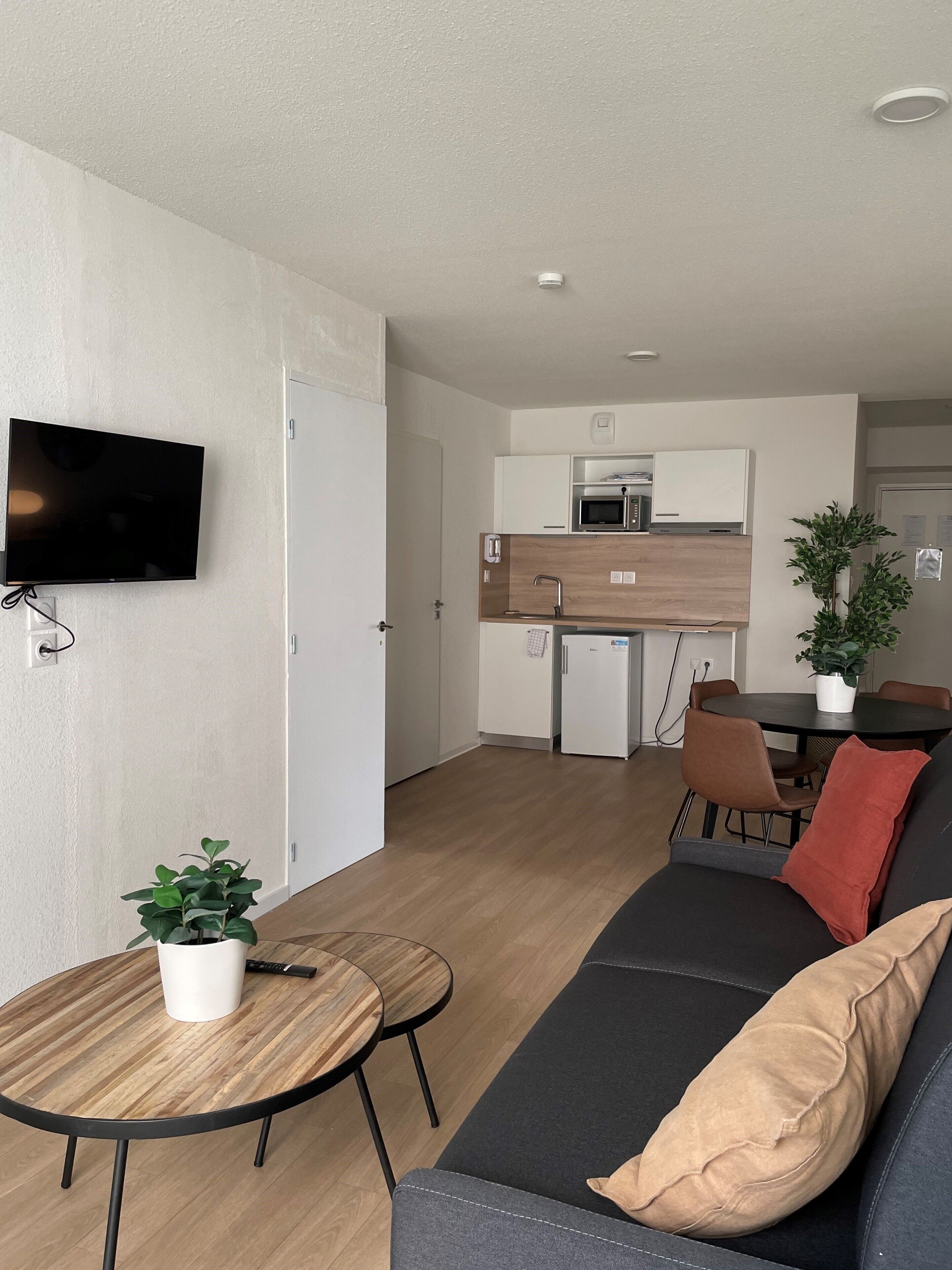 Een moderne woonkamer met een bank, een salontafel en een aan de muur bevestigde televisie.