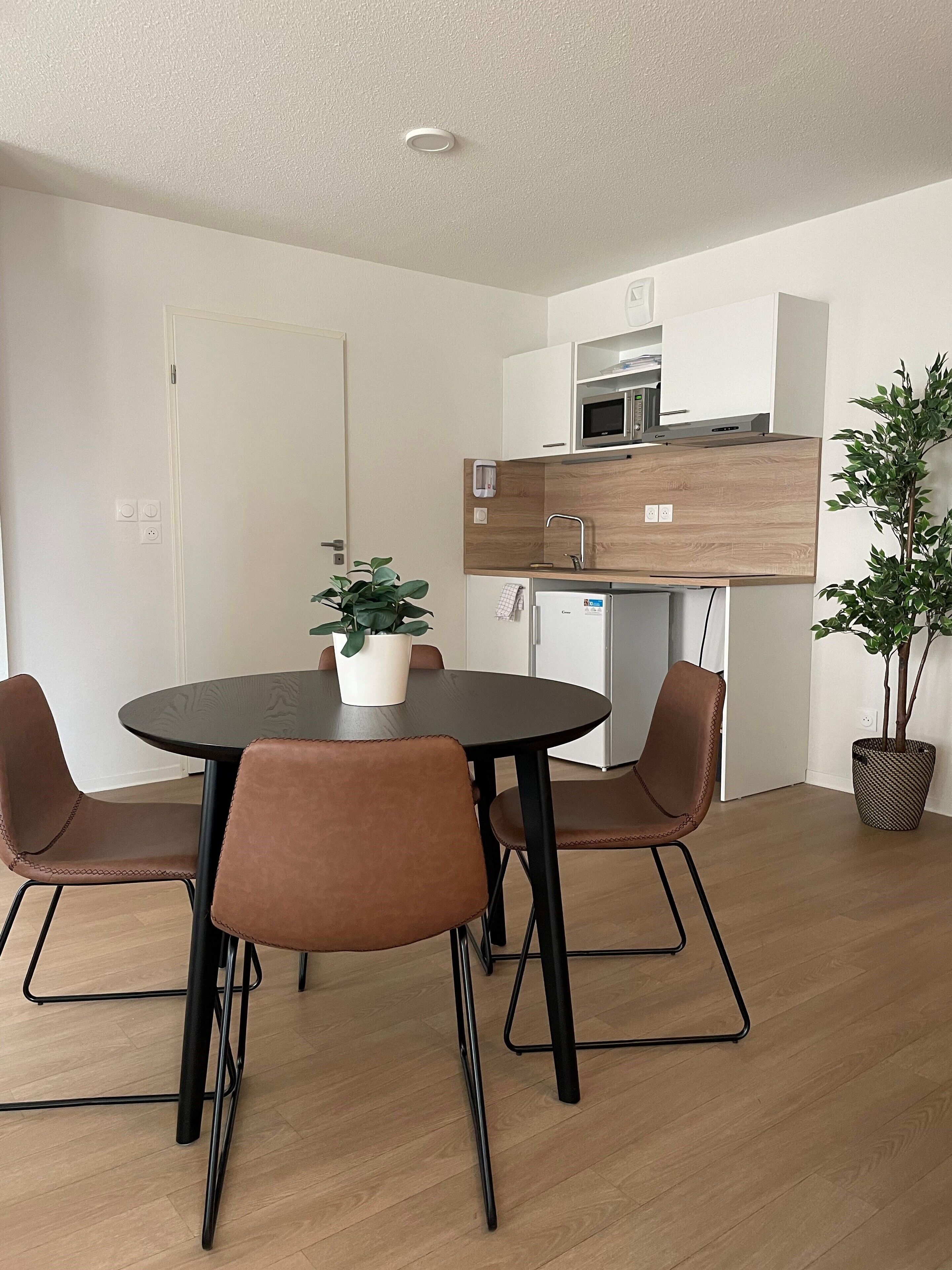 A compact kitchen with a microwave, refrigerator, and wooden countertop.