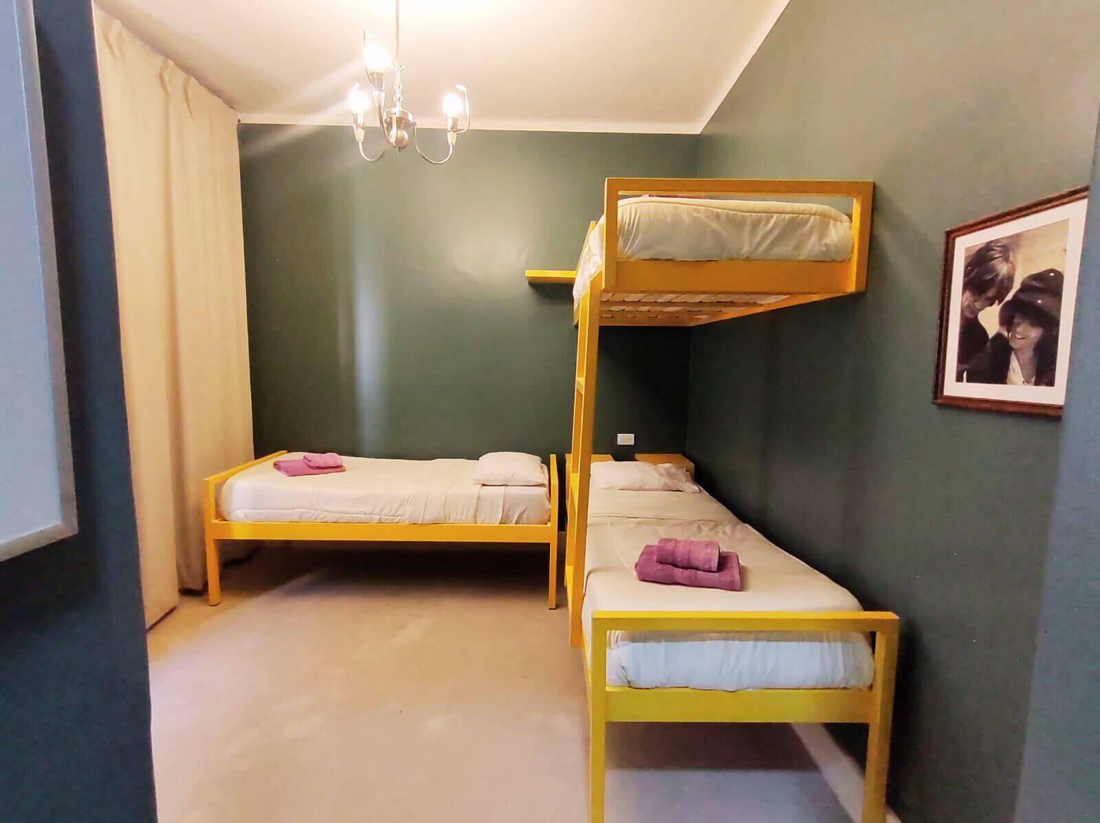 Una habitación con dos literas, un candelabro y un cuadro en la pared.