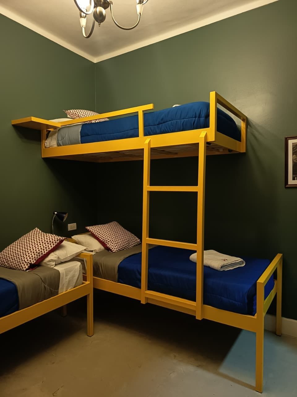A bunk bed room with a ladder, a desk, and a chair.