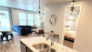A modern kitchen with a marble countertop, stainless steel sink, and wooden cabinets. - What a rooftop deck! (Washington)