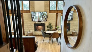 Un comedor moderno con chimenea, suelo de madera y un espejo grande.